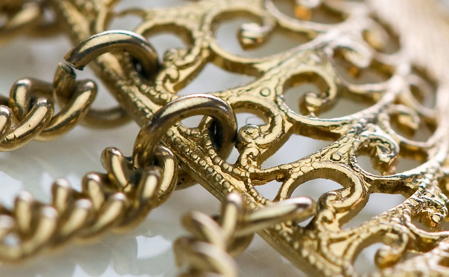 Detail of gold chain links against a scrolled filigree frame