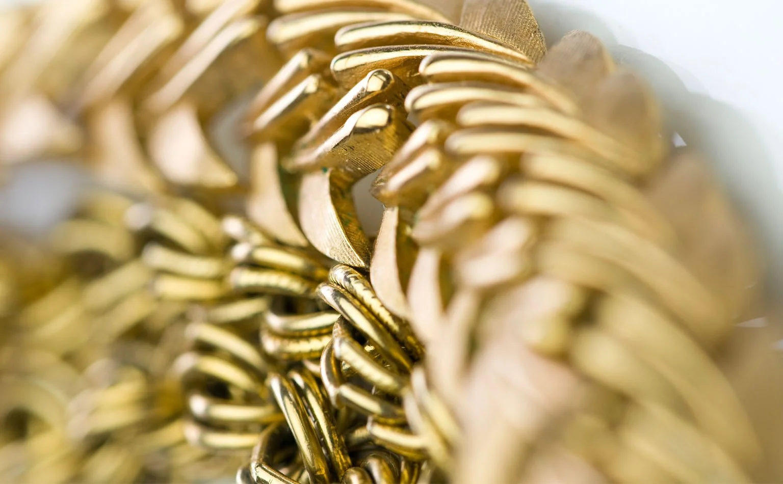 Detail of a herringbone gold chain coiled on itself 