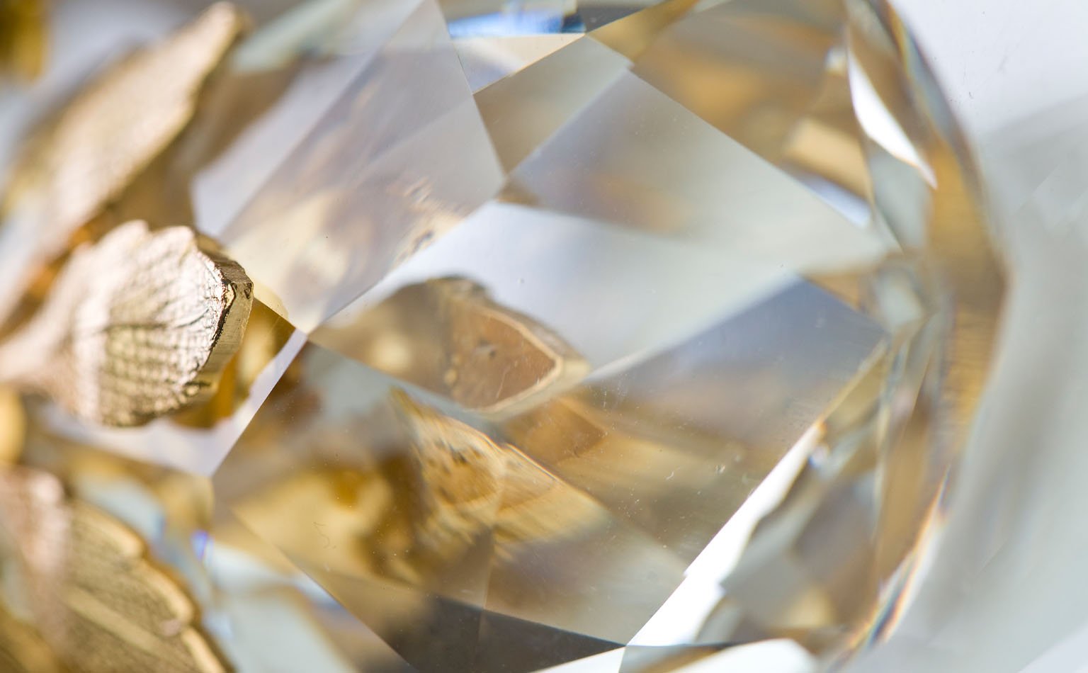 Close macro of a large faceted crystal against gold 