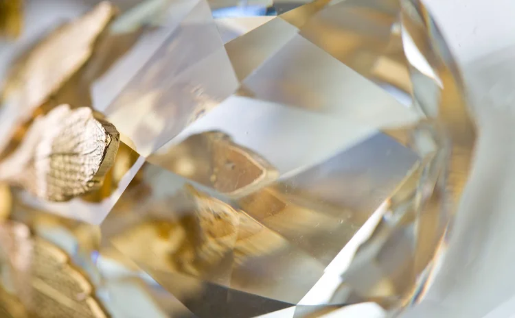 Close macro of a large faceted crystal against gold