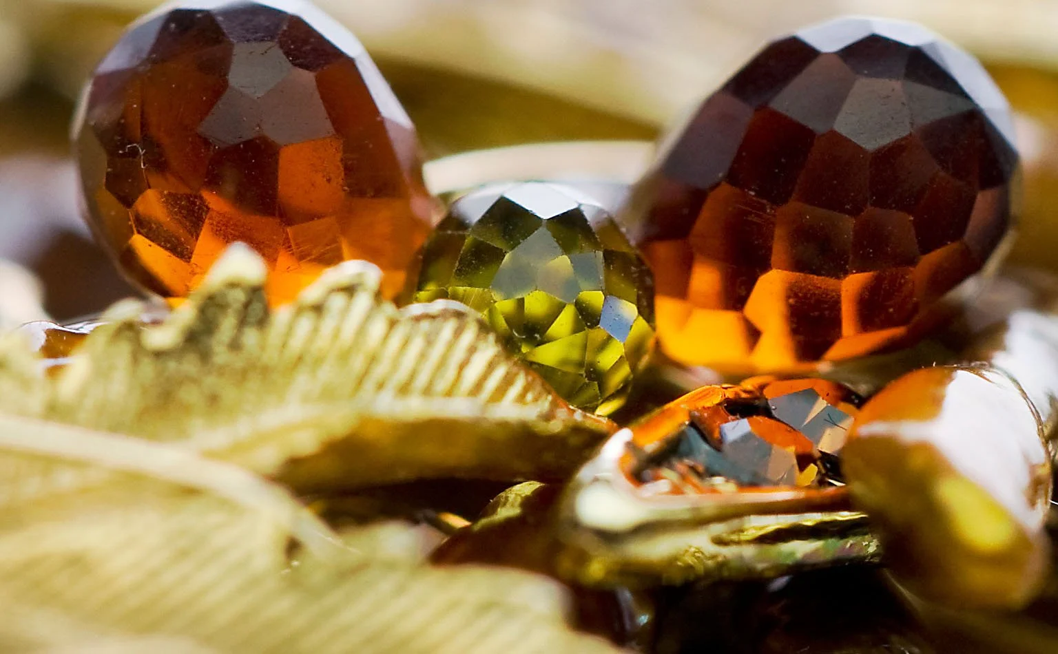 Detail of faceted amber and olive crystal on gold leaves