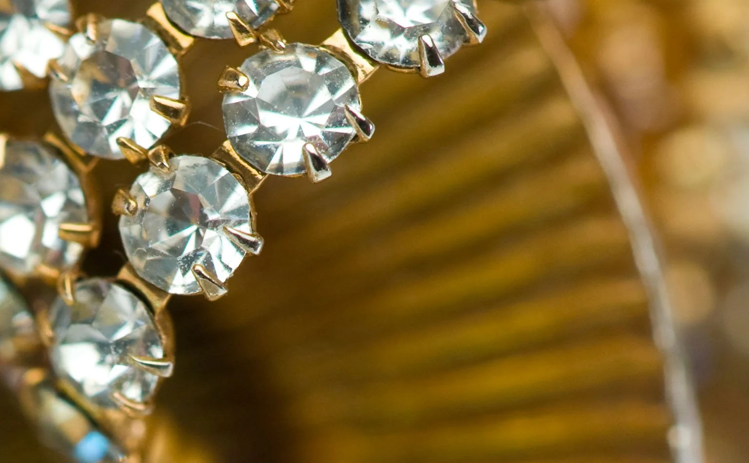Detail of clear rhinestone banding against a fluted gold fan 
