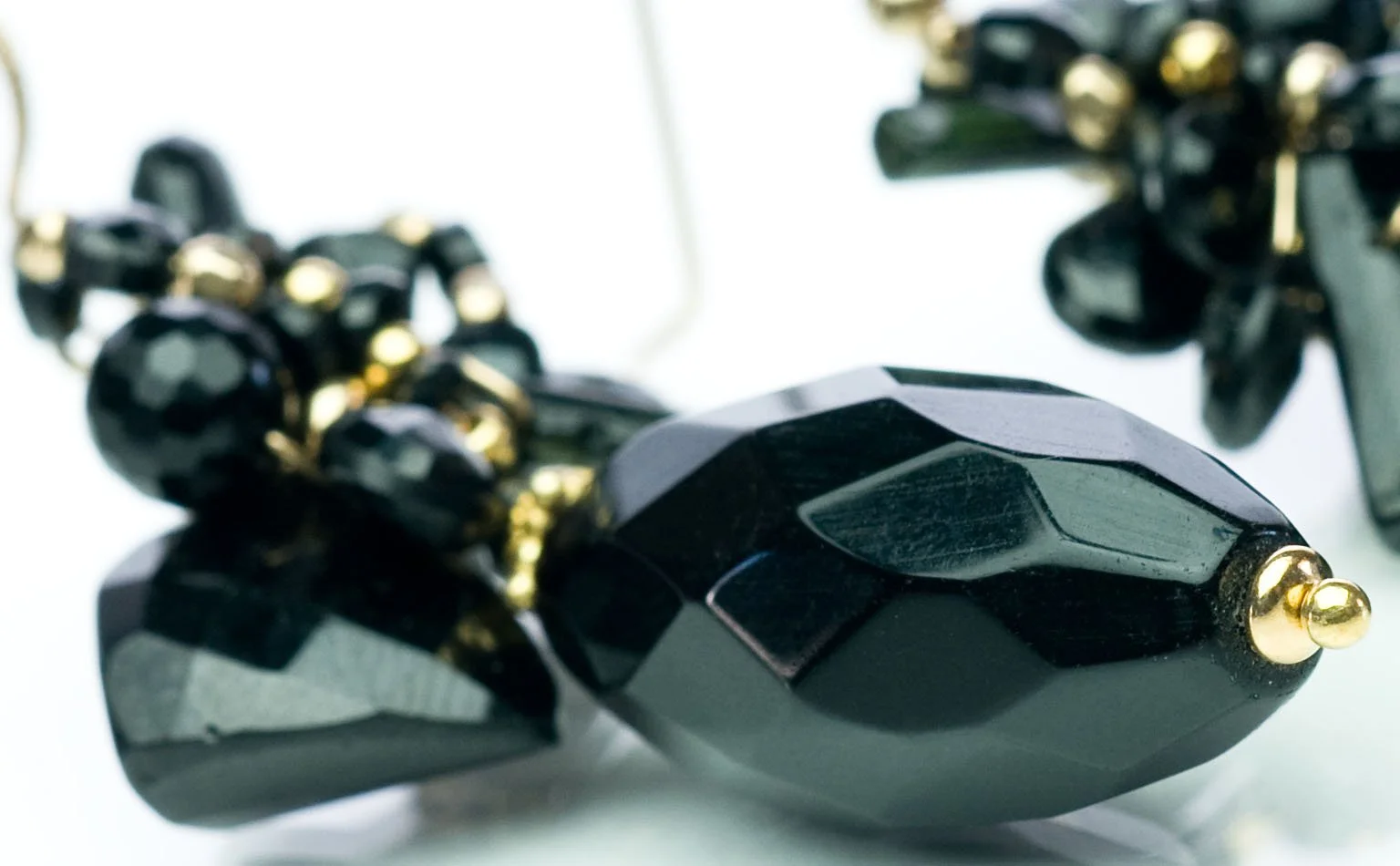 Detail of a faceted black jet briolette on a gold ear wire