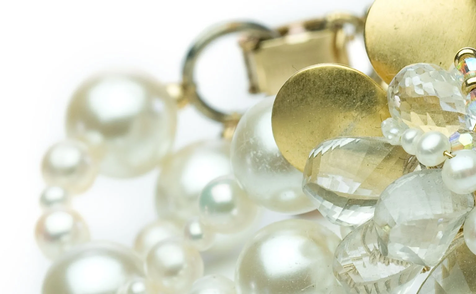 Detail of pearls, gold discs and clear crystal on a wide cuff 