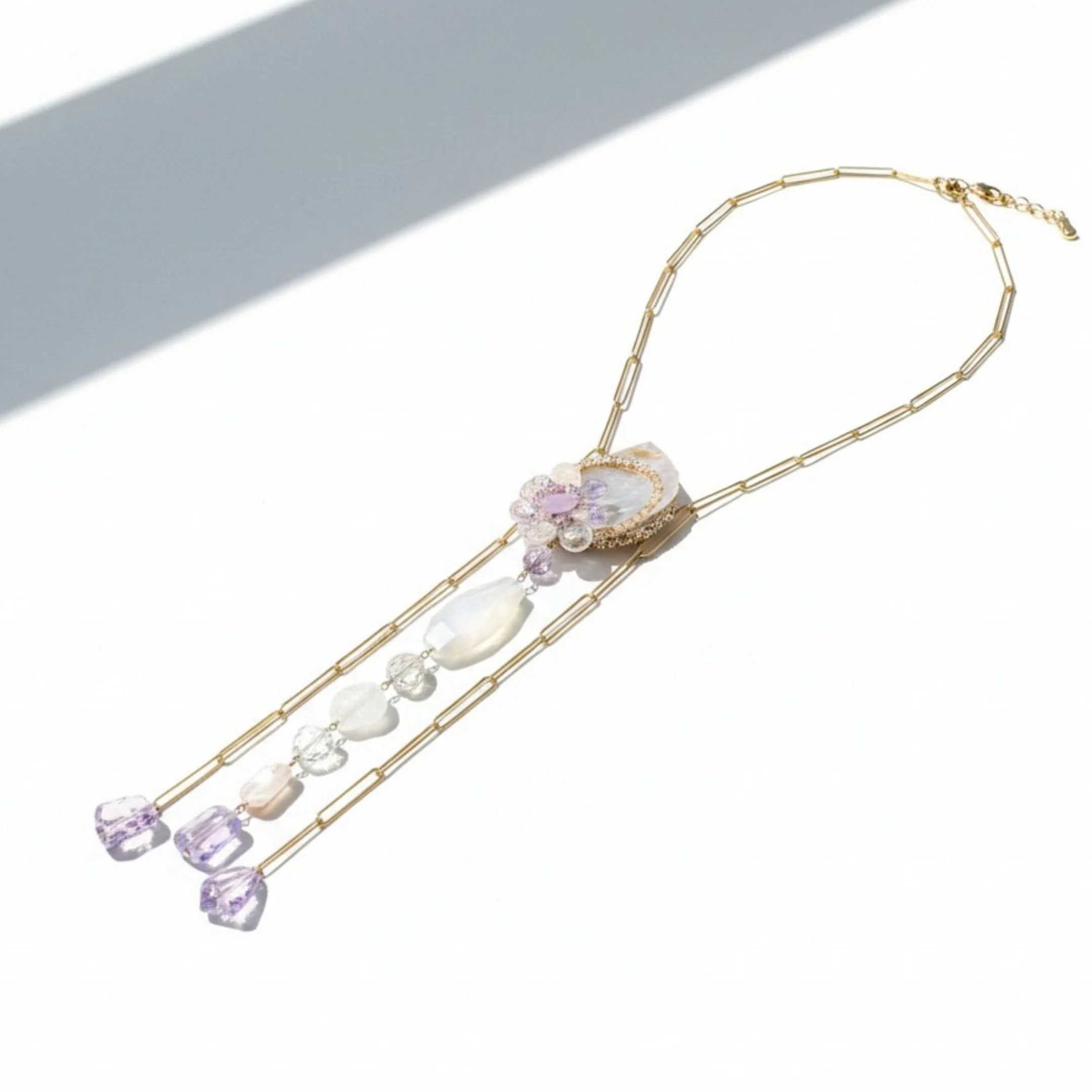 Long double-chain gold necklace with a sculptural pastel gemstone cluster, cascading pale beads, and faceted purple kunzite drops.