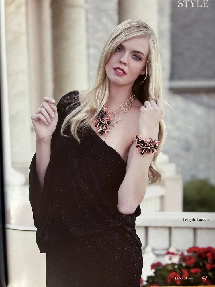 LUXZIO page 47: Leigah Larson in black wearing an Andrea Li red and gold cluster necklace and cuff