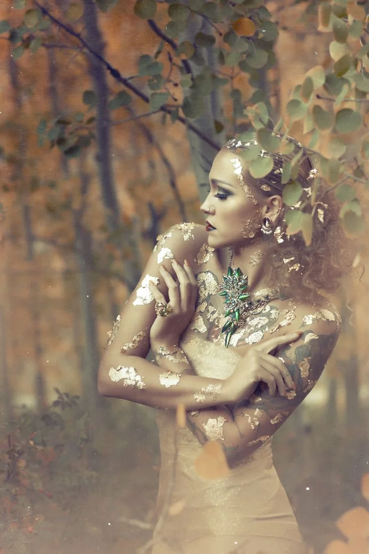 The model in gold leaf against an aspen trunk, full length