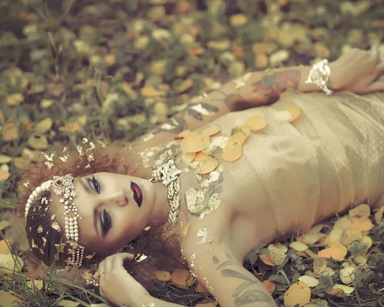 The model lying on fallen gold leaves, landscape view