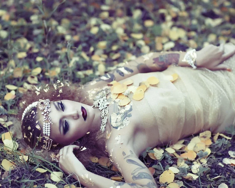Close view of the model lying on gold leaves, pearl headpiece and Andrea Li jewelry