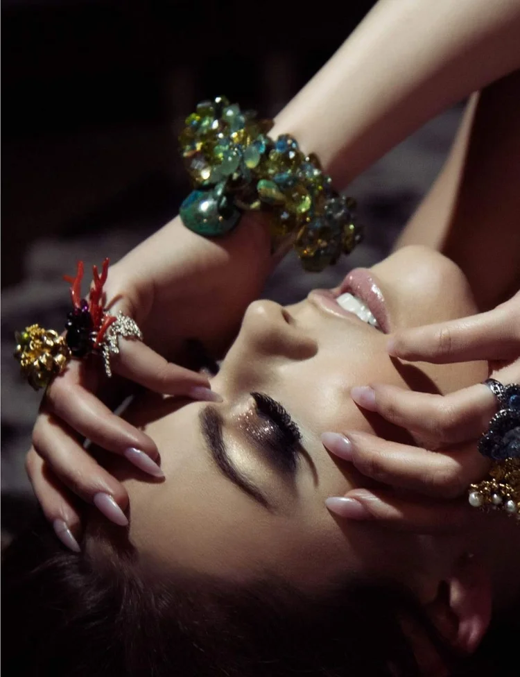 Apt 5802 page: hands framing the face, an Andrea Li green crystal cuff and coral and cluster rings