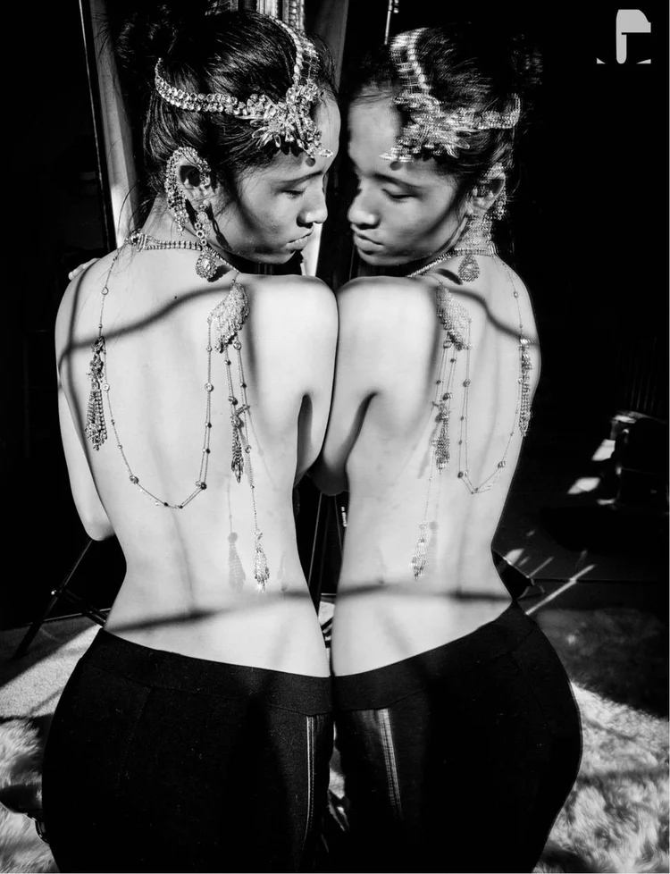 The Twins: two bare backs against a mirror, Andrea Li crystal chains falling down each spine as back necklaces