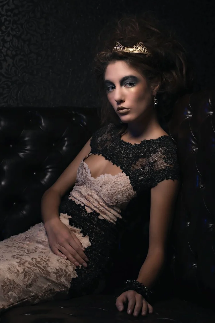 The model in black lace reclining on a dark sofa