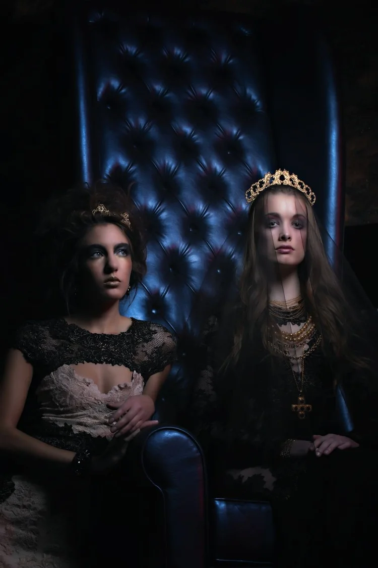 Two crowned models on the blue tufted throne