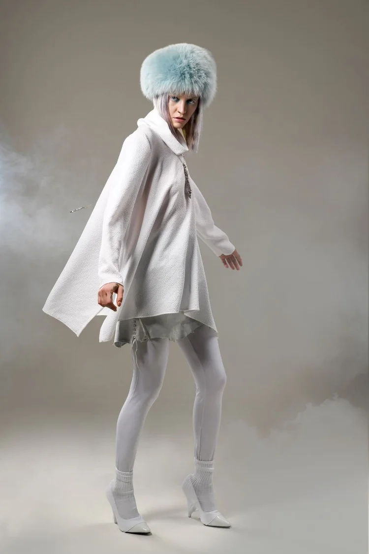 A model in a blue fur hat, white coat and boots