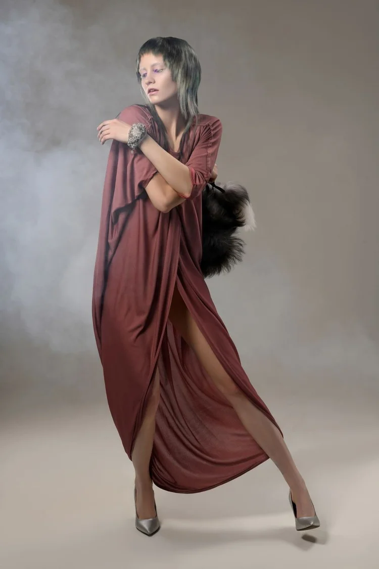 A model in a mauve draped gown with a fur clutch and cuff