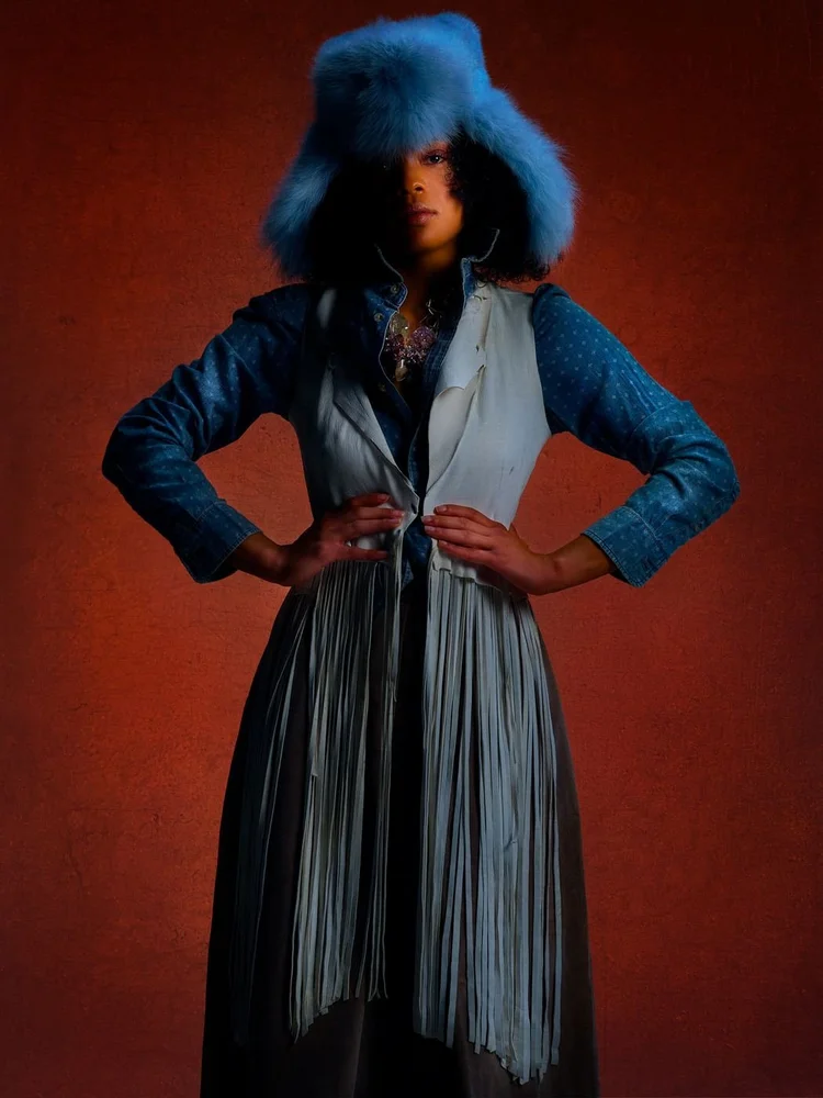 A woman in a blue fur trapper hat, denim shirt and white fringed vest, with an Andrea Li pink crystal cluster necklace
