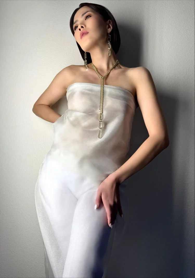 The Tamar model in a sheer strapless top, hand on hip, with an Andrea Li lariat