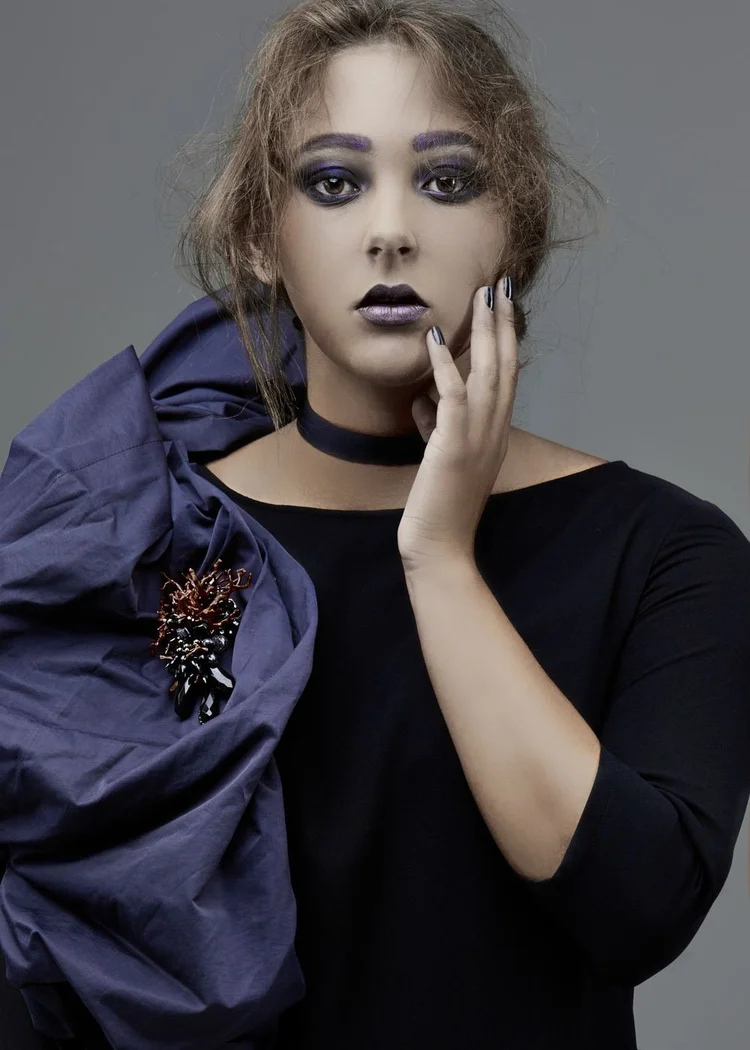 A model in a navy gown with an Andrea Li red and black brooch