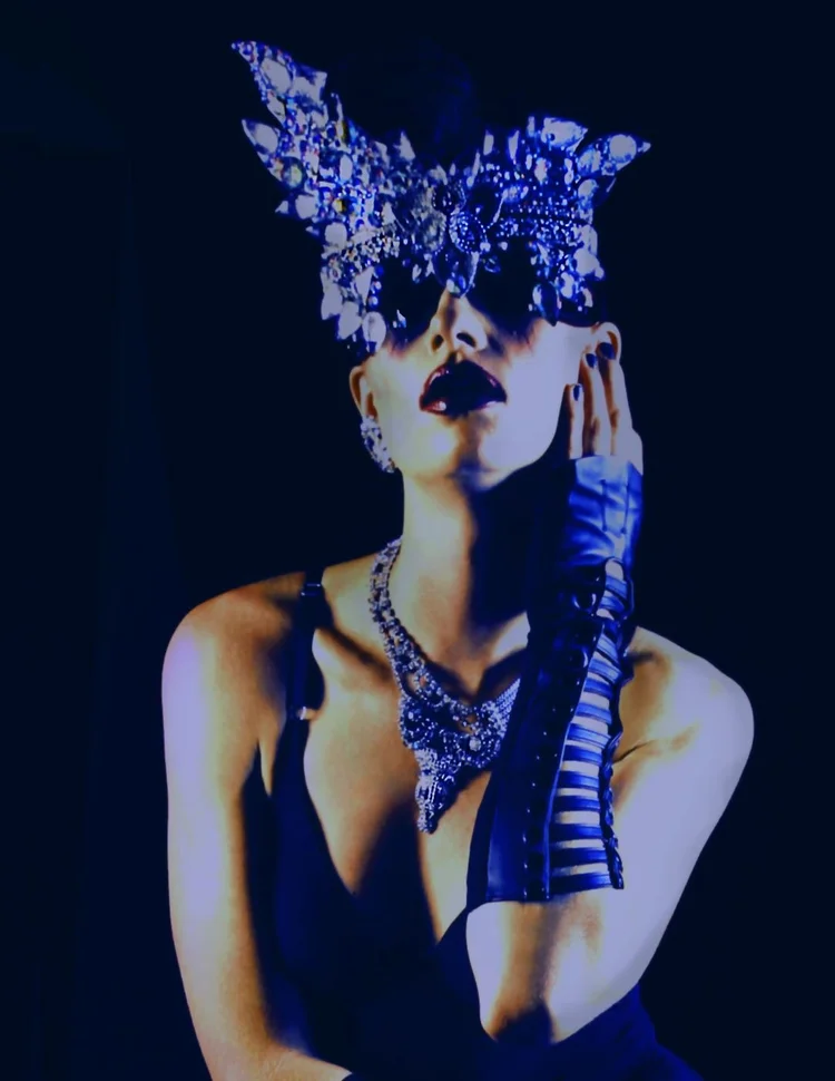 A masked model under blue light with an Andrea Li crystal necklace