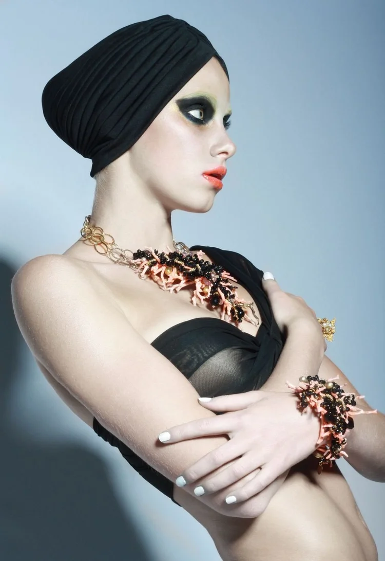 A model in a black turban with an Andrea Li coral and copper cluster necklace and cuffs