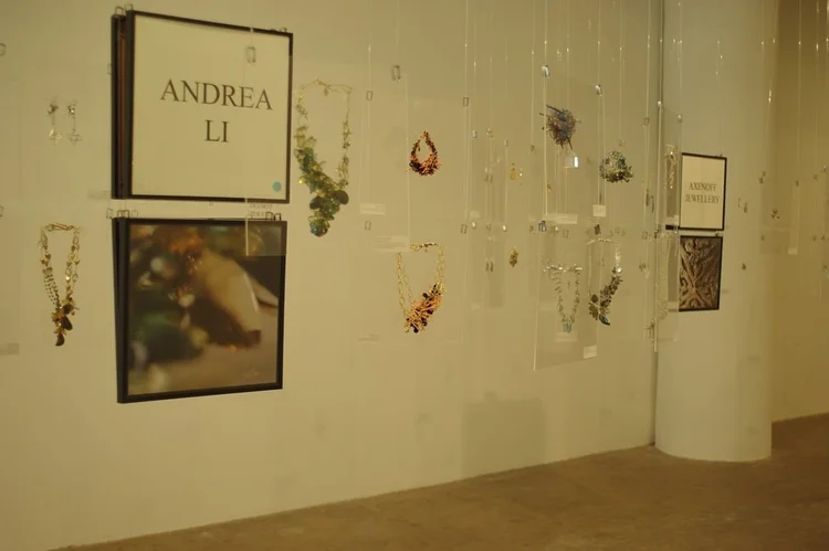 The ANDREA LI placard with a framed photograph and her cluster necklaces on clear hanging panels