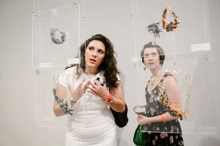 Two women talking in front of Andrea Li blue and orange cluster pieces
