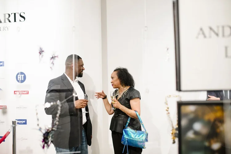 Guests talking between the sponsor wall and the edge of the Andrea Li placard