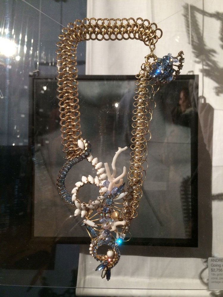 An Andrea Li gold chain necklace with white coral-like and blue rhinestone cluster over a shadow box