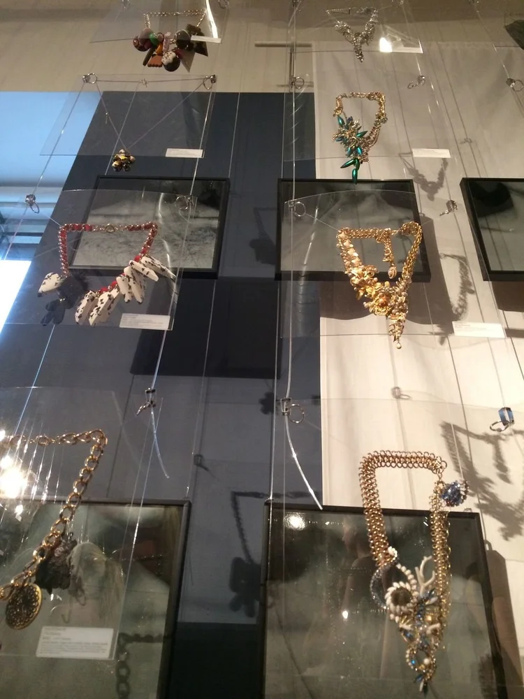 DRAFTspace 2014: a wall of hanging clear panels and shadow boxes holding Andrea Li gold vintage-component necklaces