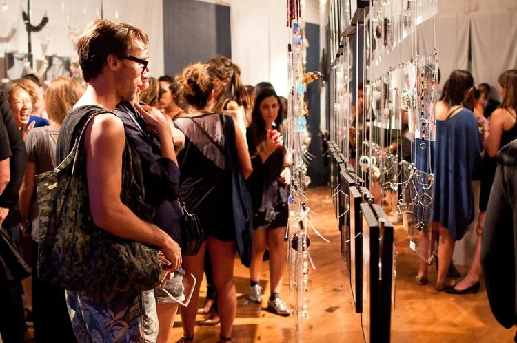 Guests at the 2014 opening among hanging clear panels and framed photographs of hands