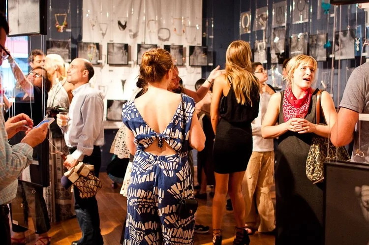 Guests at the 2014 opening among hanging clear panels and framed photographs of hands