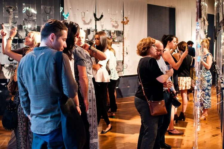Guests at the 2014 opening among hanging clear panels and framed photographs of hands