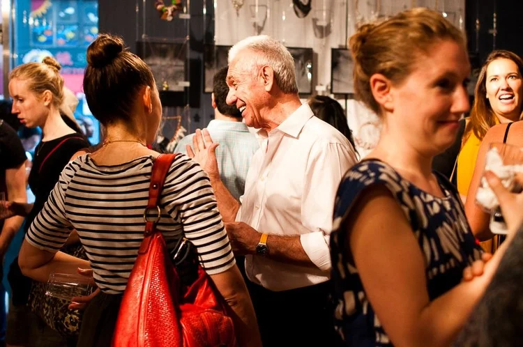 Guests at the 2014 opening among hanging clear panels and framed photographs of hands