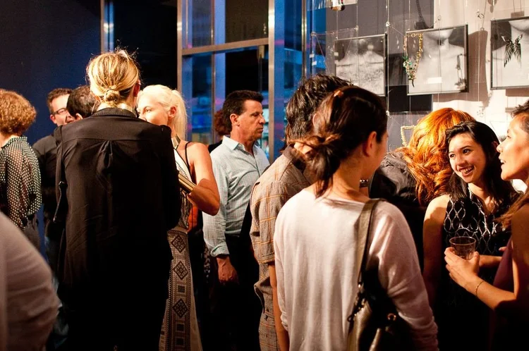 Guests at the 2014 opening among hanging clear panels and framed photographs of hands