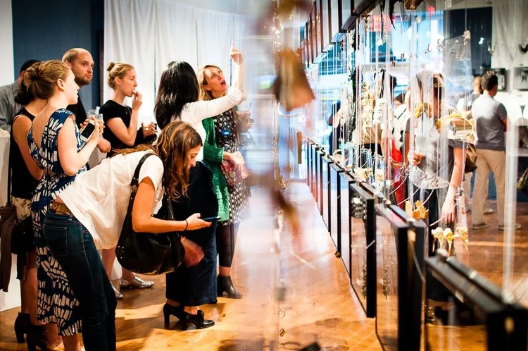 Guests at the 2014 opening among hanging clear panels and framed photographs of hands