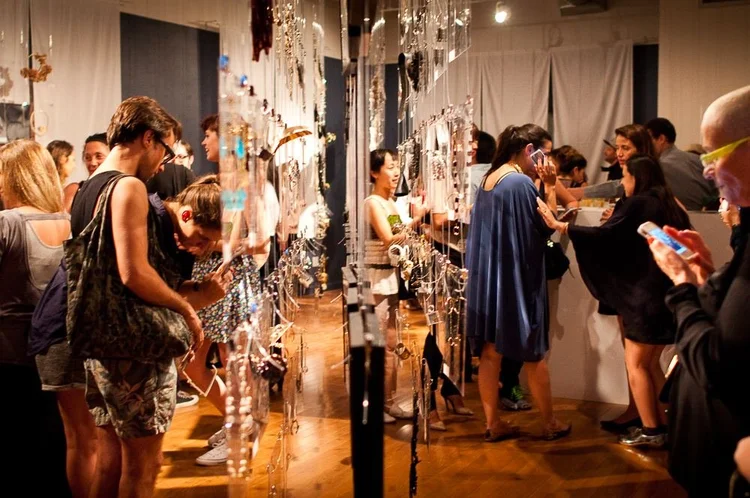 Guests at the 2014 opening among hanging clear panels and framed photographs of hands