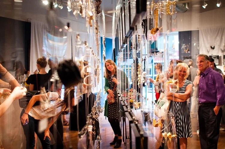 Guests at the 2014 opening among hanging clear panels and framed photographs of hands