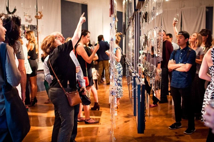 Guests at the 2014 opening among hanging clear panels and framed photographs of hands