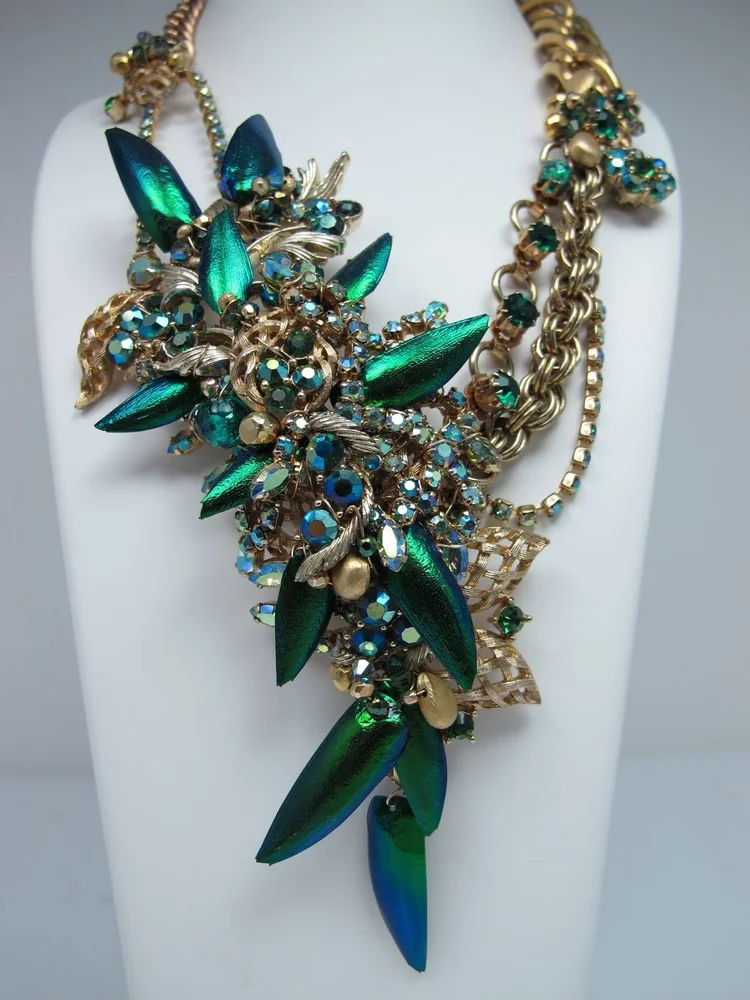 Studio photo on a bust: a gold chain necklace with a green iridescent cluster