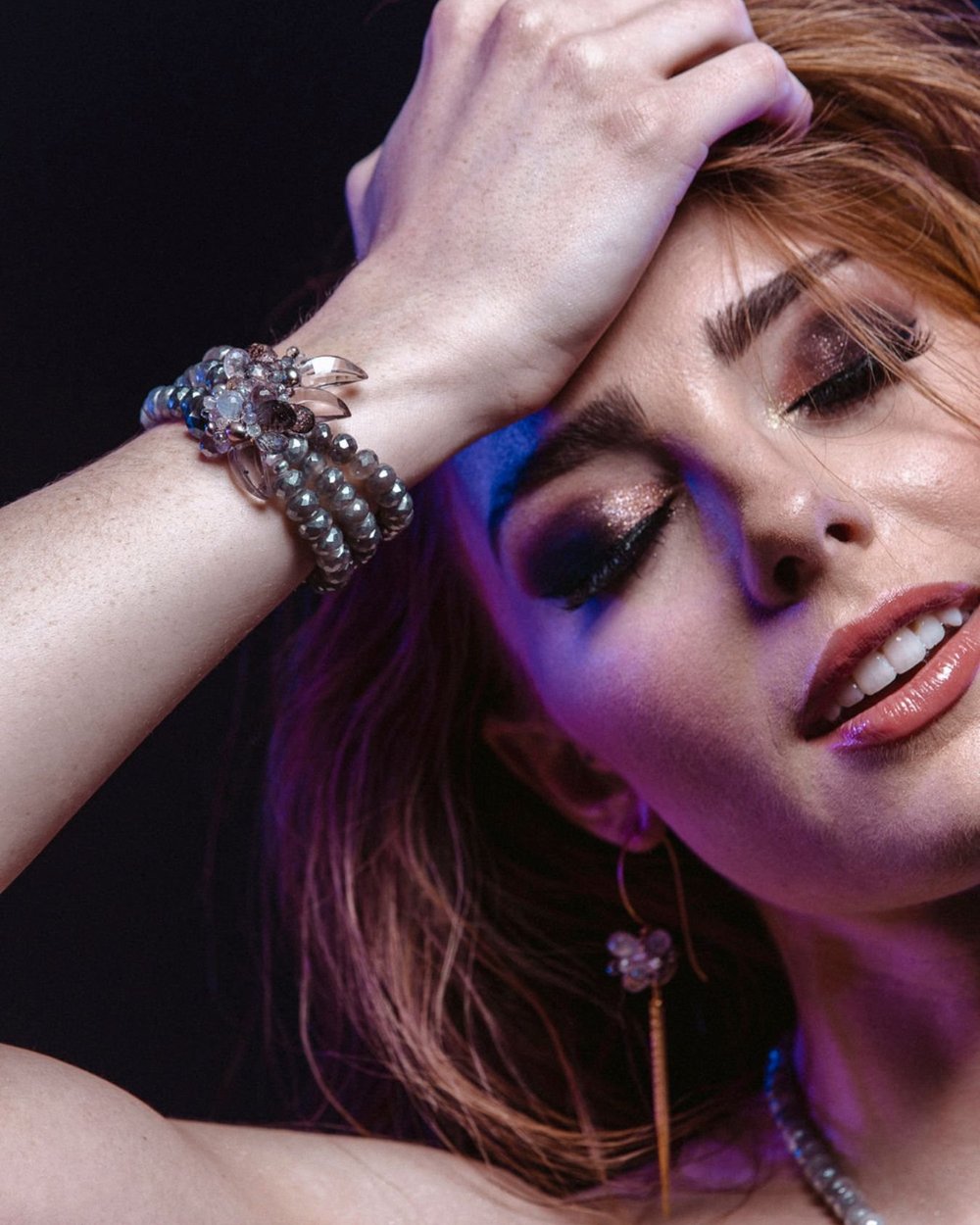 A red-haired model with her arm over her head, wearing an Andrea Li moonstone and pearl bracelet, by Andrea Li