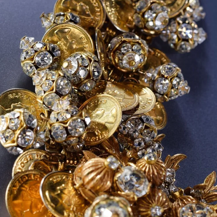 Close-up of a pile of vintage gold coins, crystal beads and gold filigree jewelry components