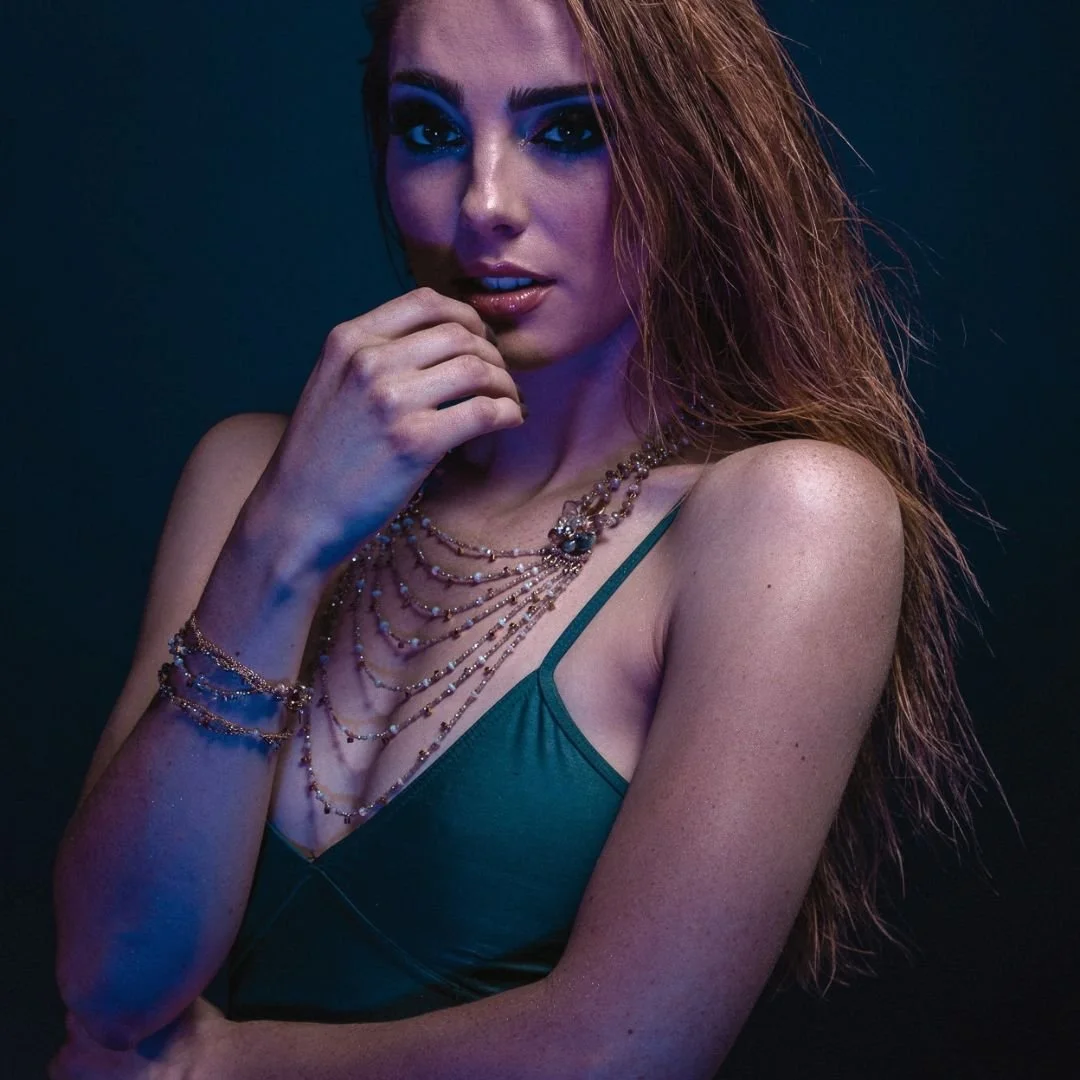A model in a teal camisole wearing an Andrea Li multi-strand beaded necklace whose strands fall at graduated lengths, with a matching multi-strand bracelet