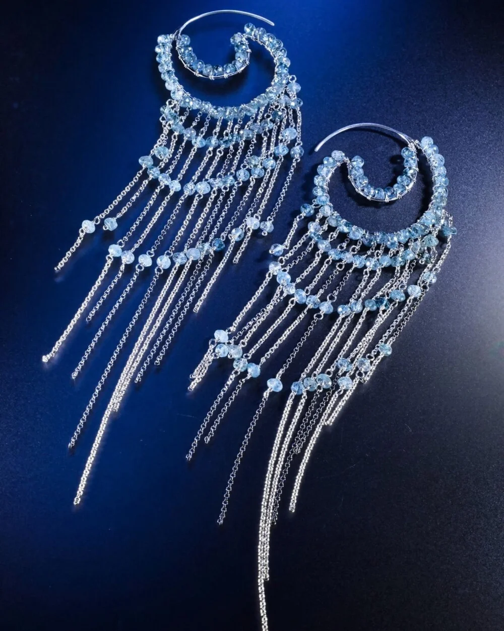 Andrea Li silver crescent earrings with cascading chains of pale blue gemstones on deep blue, by Andrea Li