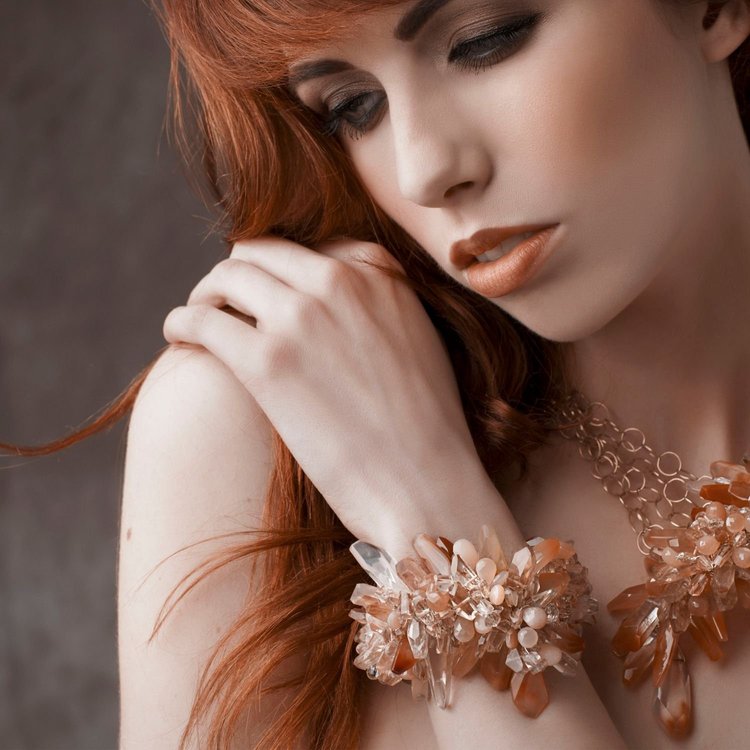 A red-haired model with her hand on her shoulder, wearing an Andrea Li peach gemstone statement cuff, by Andrea Li