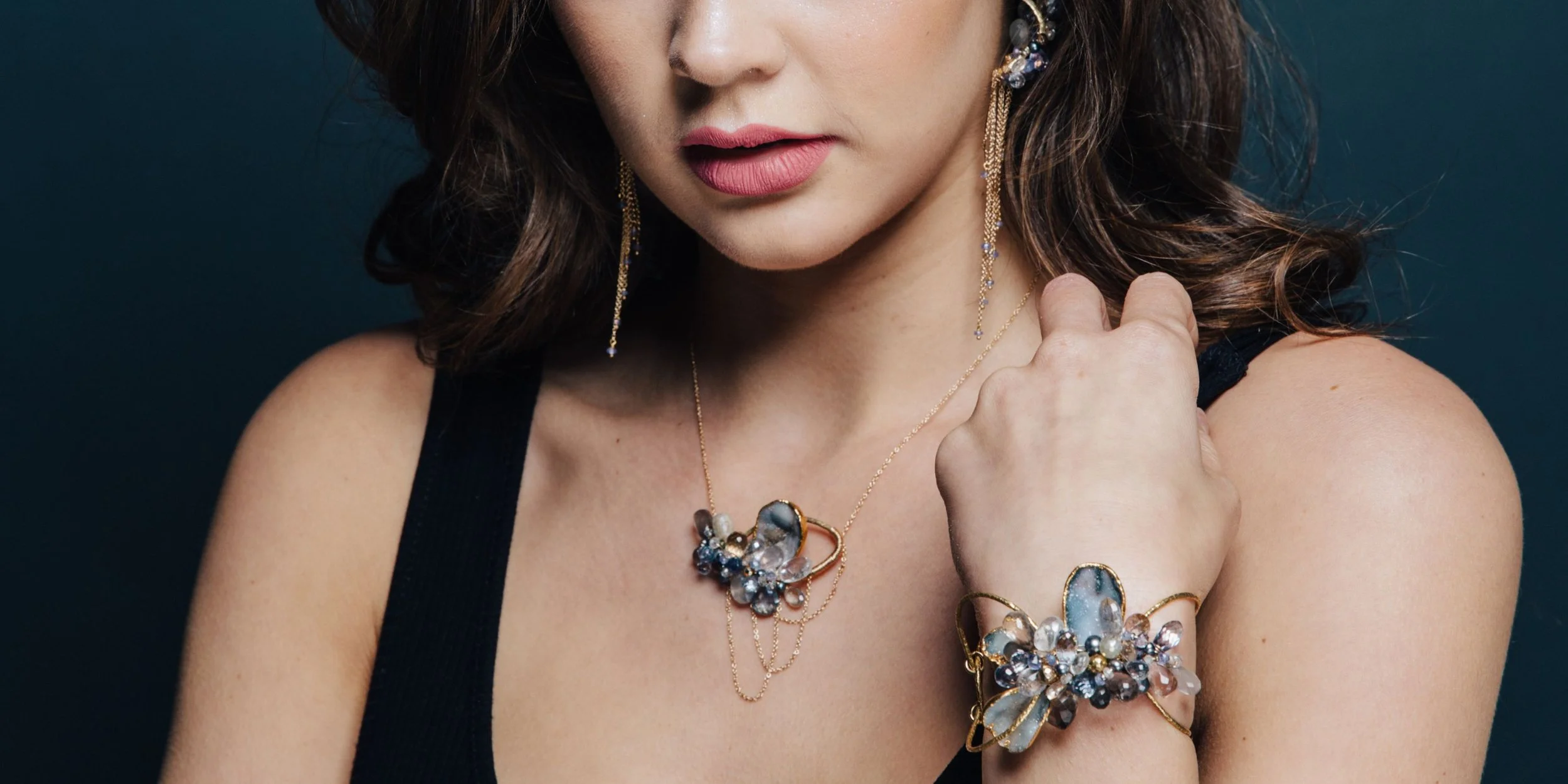 A model in a black top wearing an Andrea Li sapphire cluster cuff and a sapphire pendant, by Andrea Li