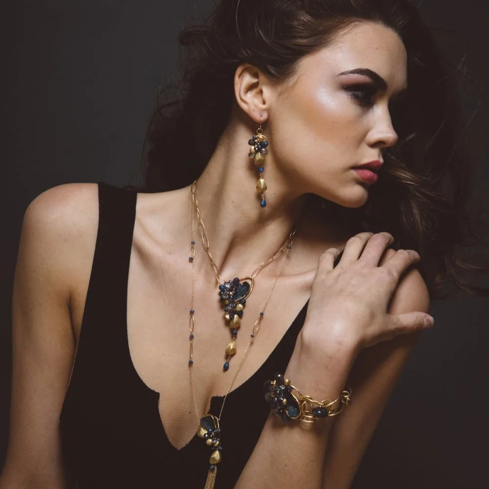 A model in a black top wearing a long Andrea Li gemstone pendant necklace and a matching gemstone bracelet