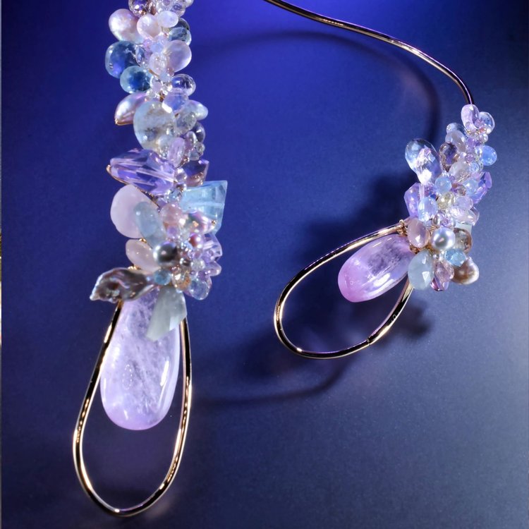 The Pink Kunzite Choker: a gold collar ending in clusters of lilac, aqua and clear gemstones around pale pink drops, on a blue backdrop