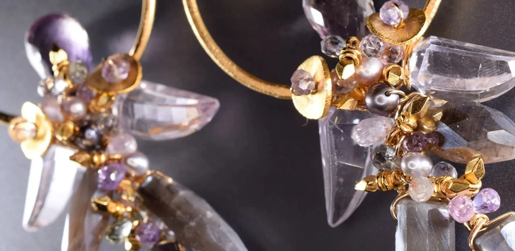 Close view of Andrea Li statement earrings: clear crystal points and gold discs with clusters of lavender and pink gemstones on gold hoops