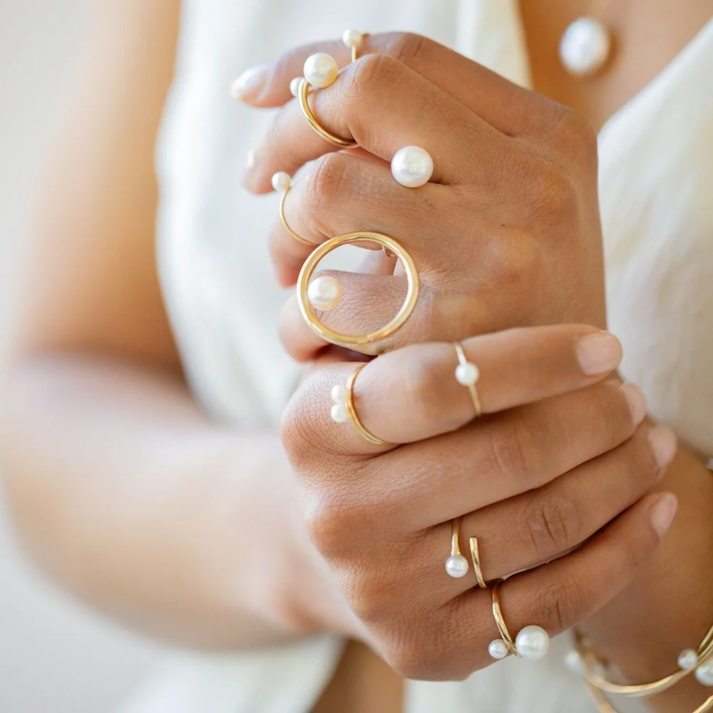 Close view of hands stacked with Andrea Li gold and pearl rings, by Andrea Li