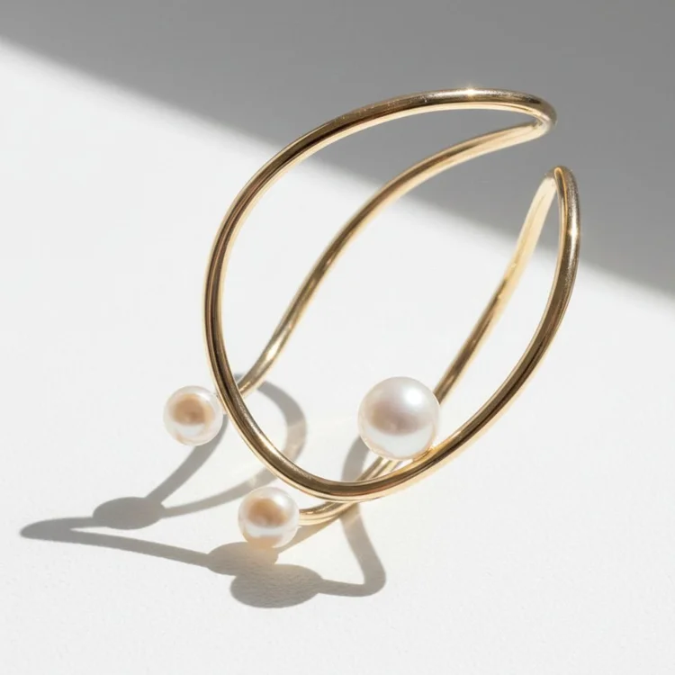 Sculptural gold cuff bracelet with a pearl